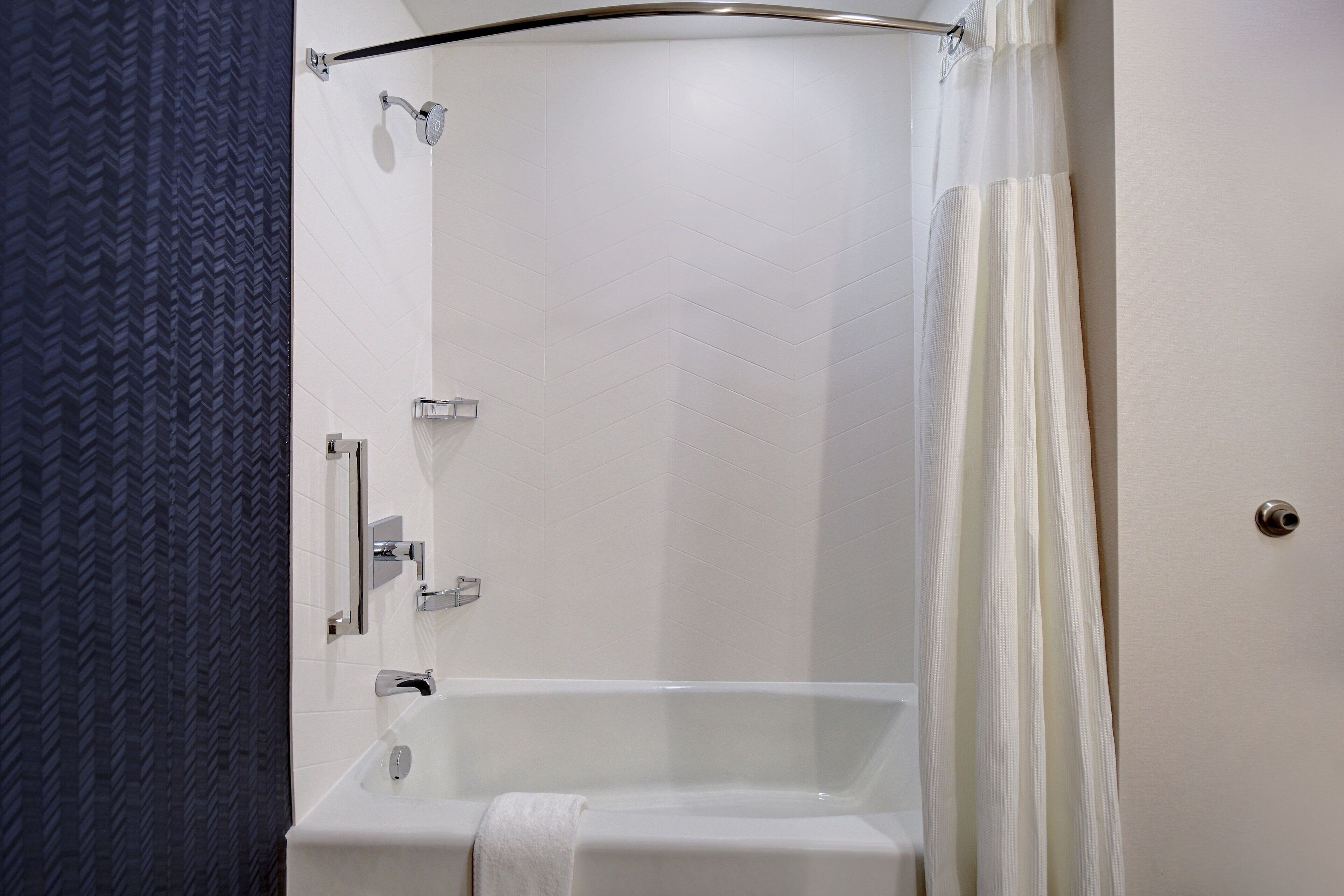 A modern bathroom with a bathtub, a shower, and a towel rack.