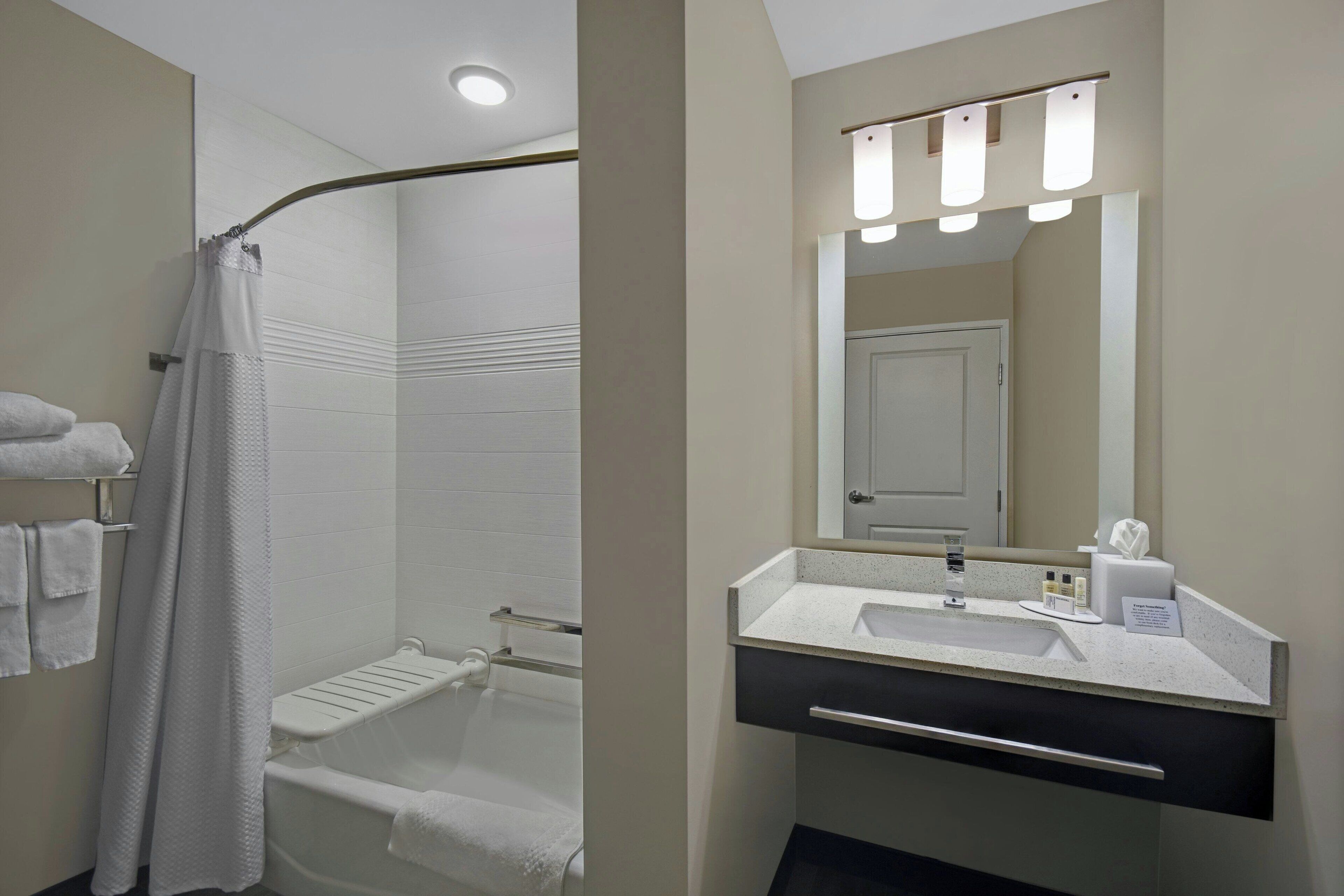 A modern bathroom with a shower, a sink, and a mirror.