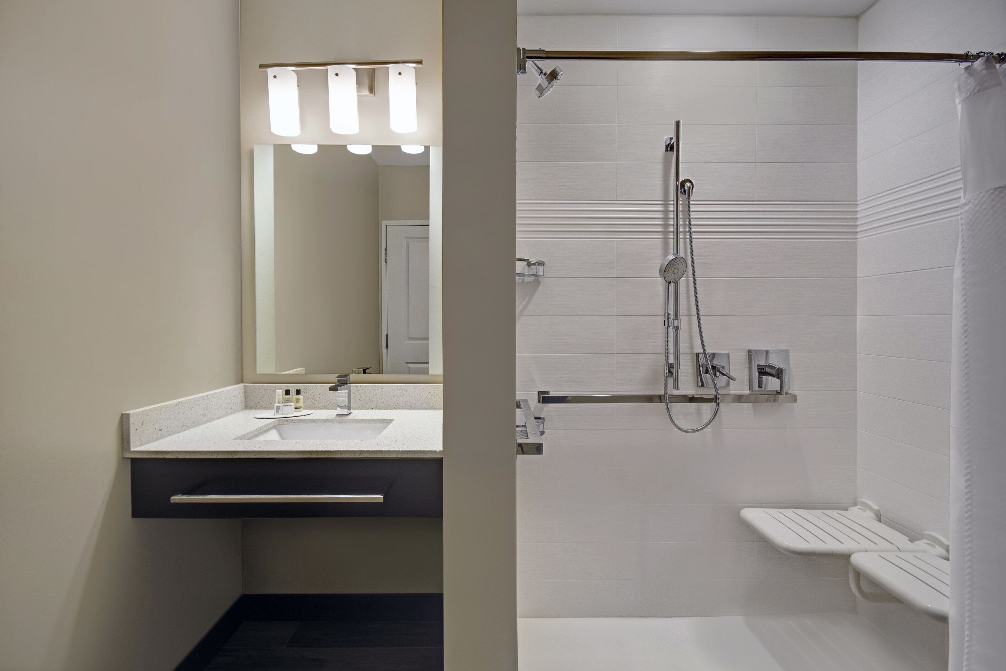Un baño moderno con lavamanos, espejo y ducha.