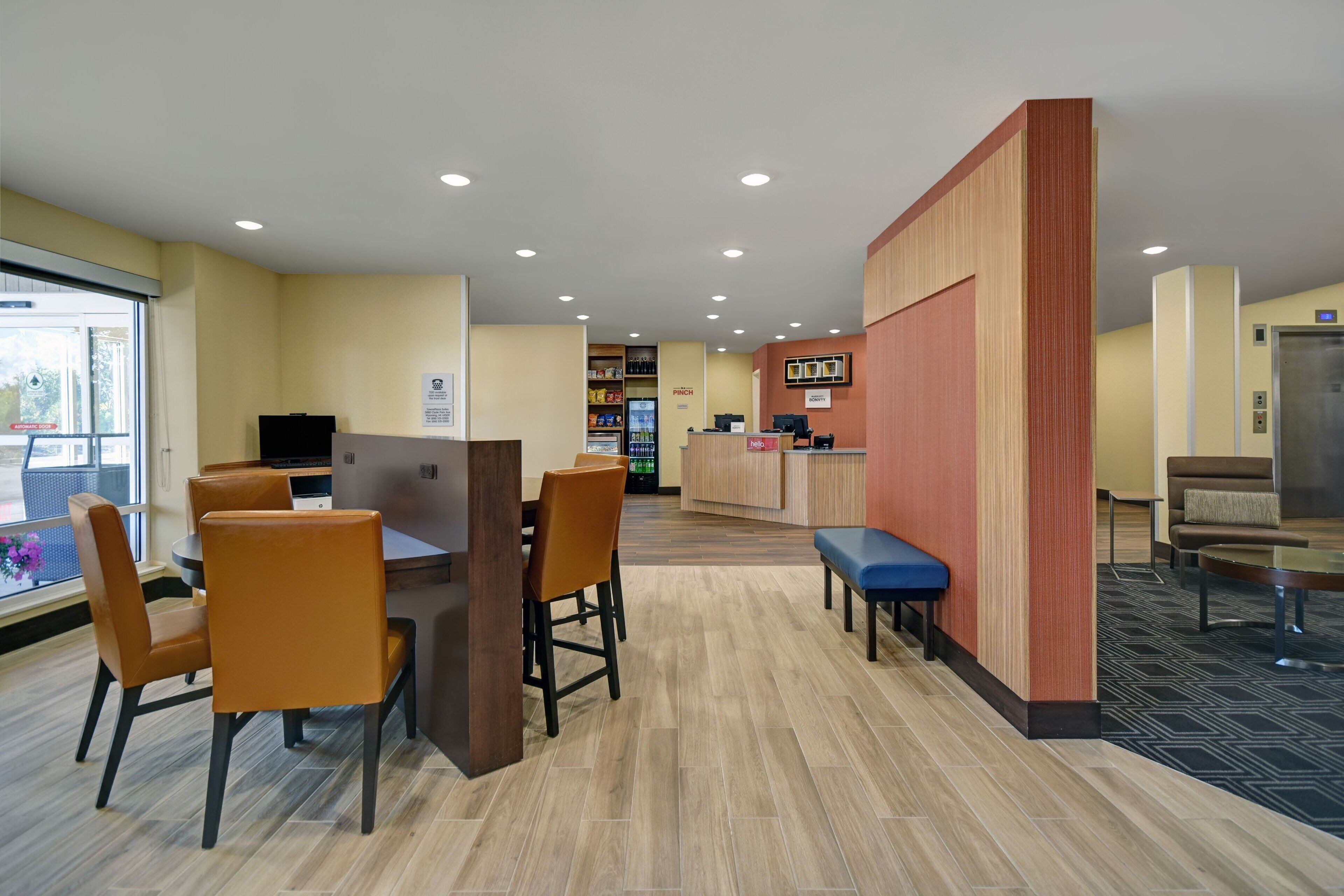A hotel lobby with a reception desk, seating area, and a vending machine.