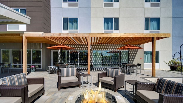 An outdoor patio with wicker furniture, a central fire pit, and a covered seating area.