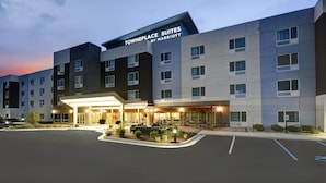 A modern hotel with multiple floors, a well-lit entrance, and outdoor seating areas.