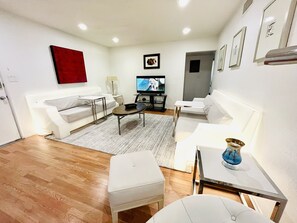 A modern living room with a white sofa, a coffee table, and a TV.