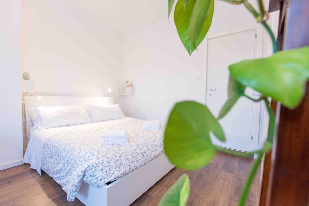 A bedroom with a bed, bedside tables, and a door.