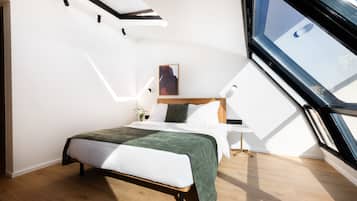 Quarto moderno com claraboia, cama com manta verde e mesa de cabeceira com abajur.
