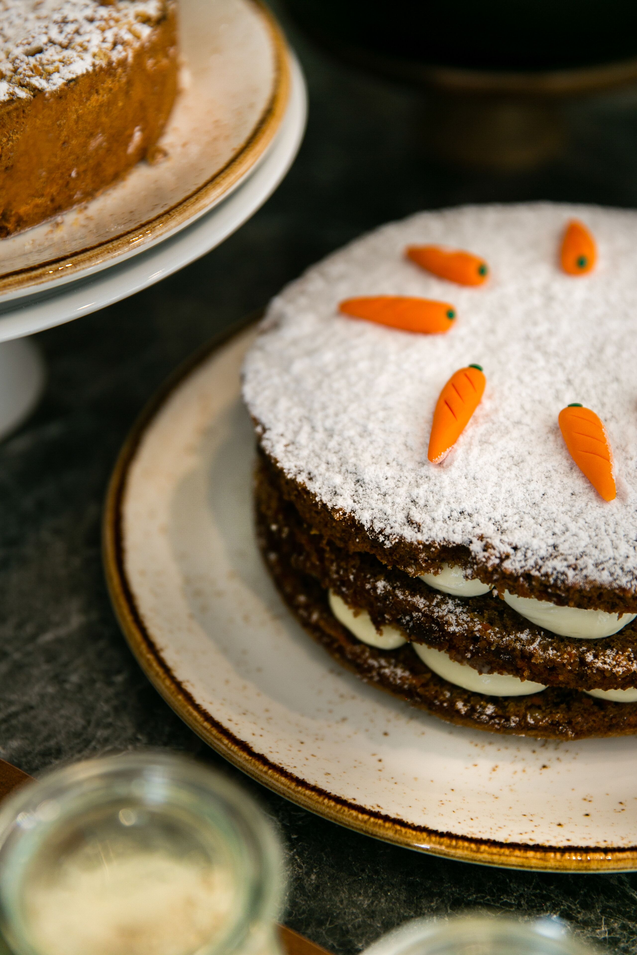 A cake with white frosting and carrot decorations on a plate.