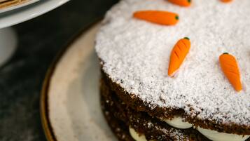 A cake with white frosting and carrot decorations on a plate.