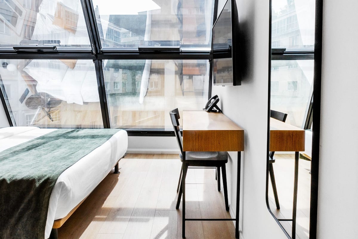 A modern bedroom with a bed, a desk, and a TV.