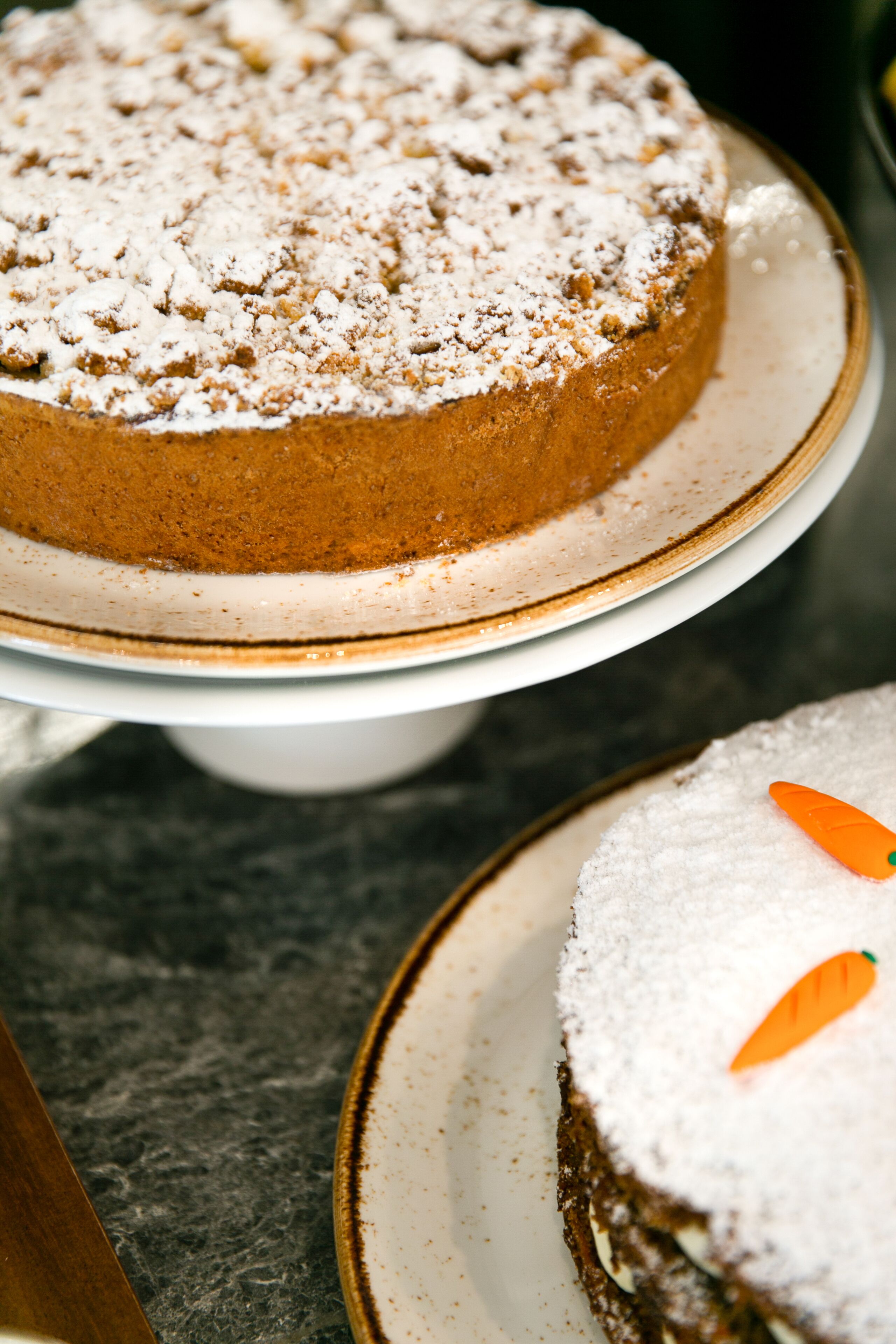 A round cake with powdered sugar on a white cake stand.