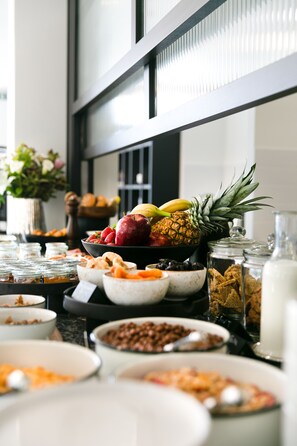 A buffet table with various food items including fruits, nuts, and cereals. - Noa Hotel (Thessaloniki)