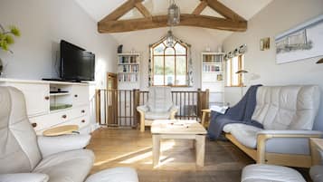 A cozy living room with a television, bookshelves, and comfortable seating.