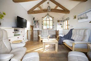 Un salon chaleureux avec un téléviseur, des étagères à livres et des fauteuils confortables.