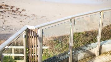 Una escalera de madera que lleva a una playa, con vista despejada al océano.