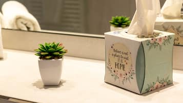 En tissueskasse med blomstermønster og en besked på en badeværelsesbordplade.
