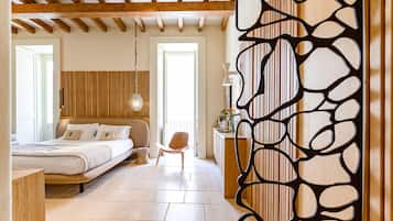A bedroom with a bed, bedside table, chair, and a decorative wall panel.