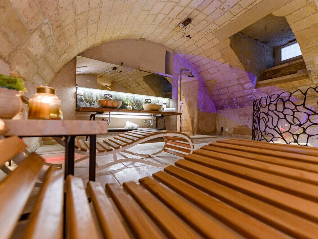 An interior with a wooden bench, a table, and a kitchen area with a window.
