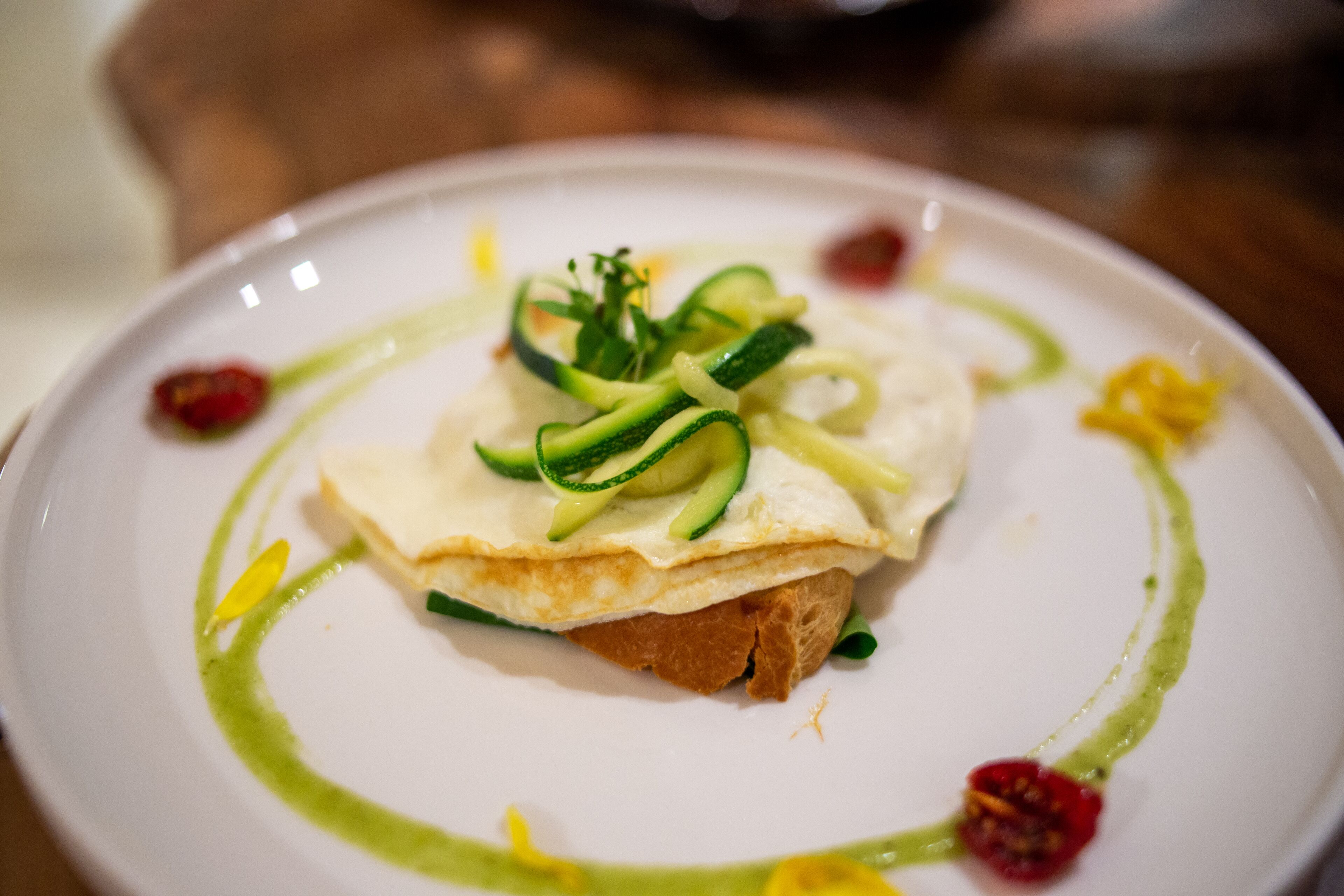 Um prato com um omelete dobrado, abobrinha e guarnições.