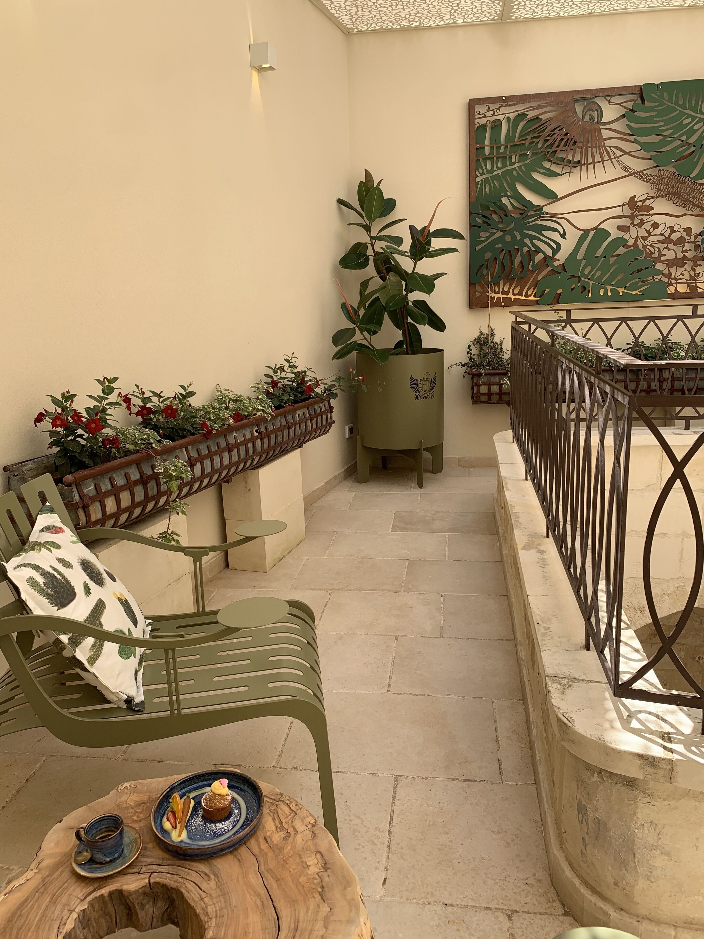 A terrace with a wooden table, a green bench, and a potted plant.