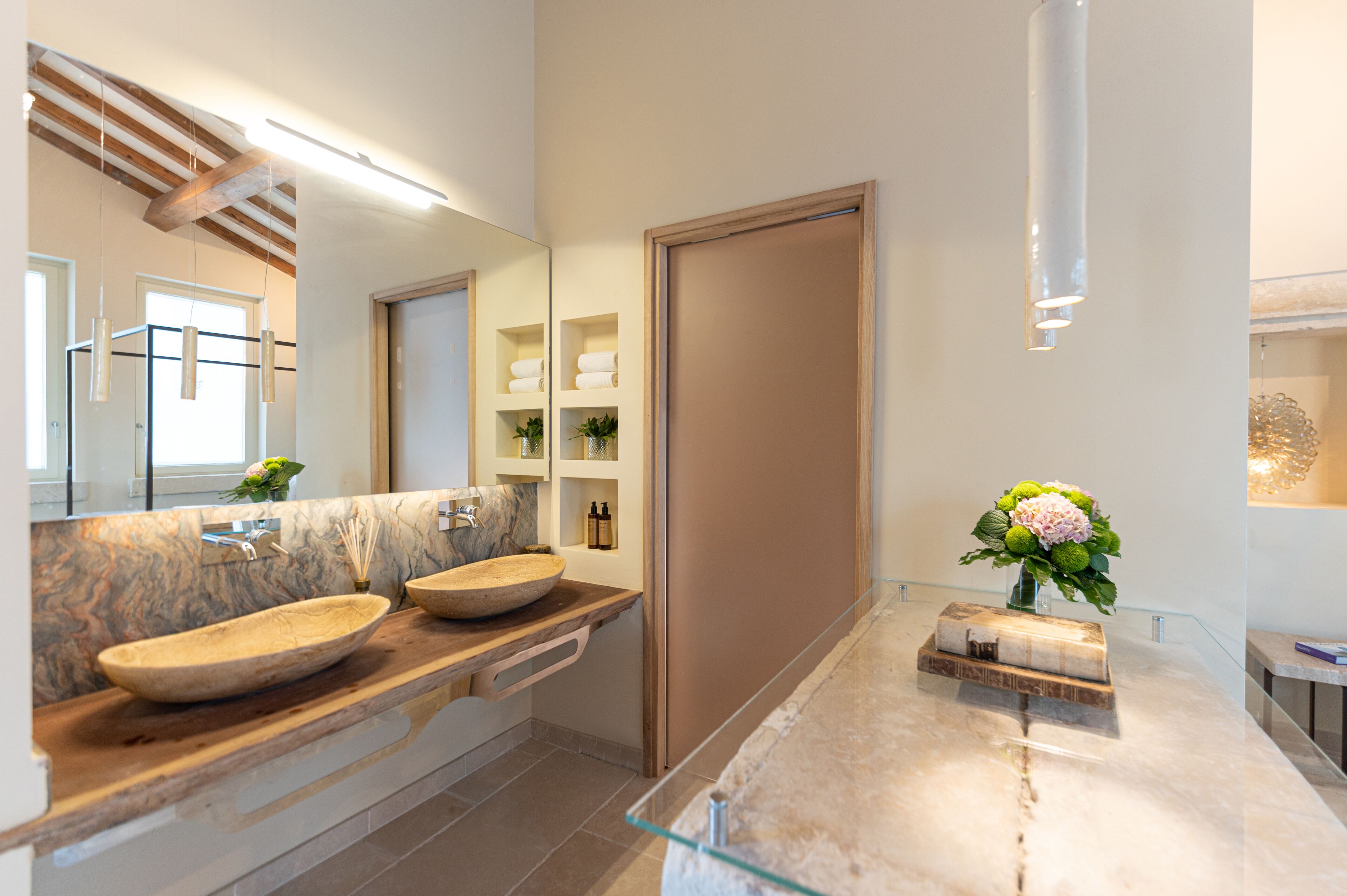 Un baño moderno con dos lavamanos grandes, un espejo y una cabina de ducha de vidrio.
