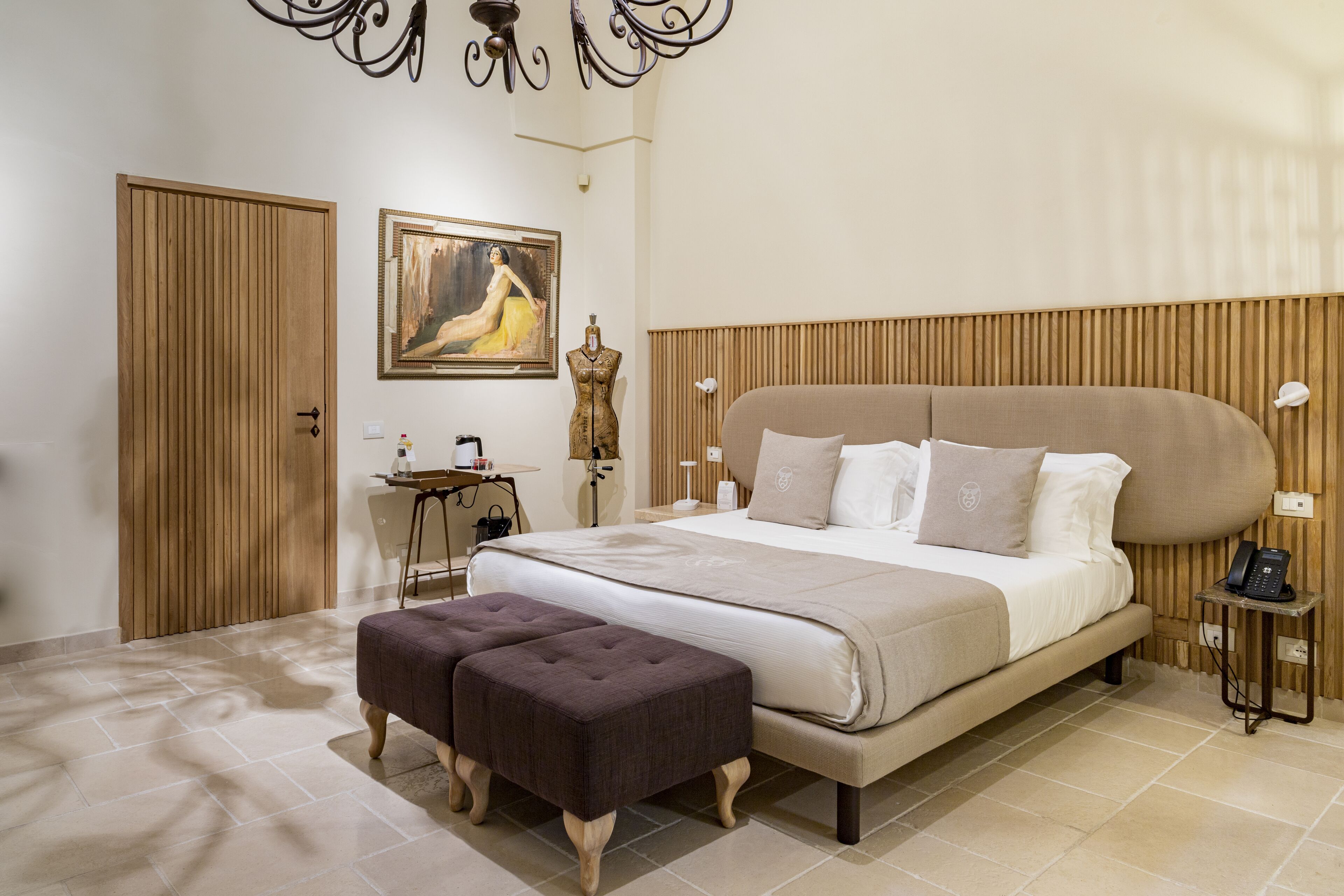 Un dormitorio con una cama grande, cabecera de madera, una mesita de noche, escritorio, silla, un cuadro y un armario.