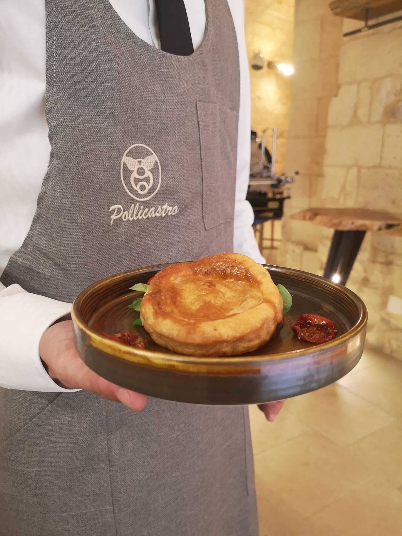 Una persona con delantal gris sosteniendo un plato con comida.