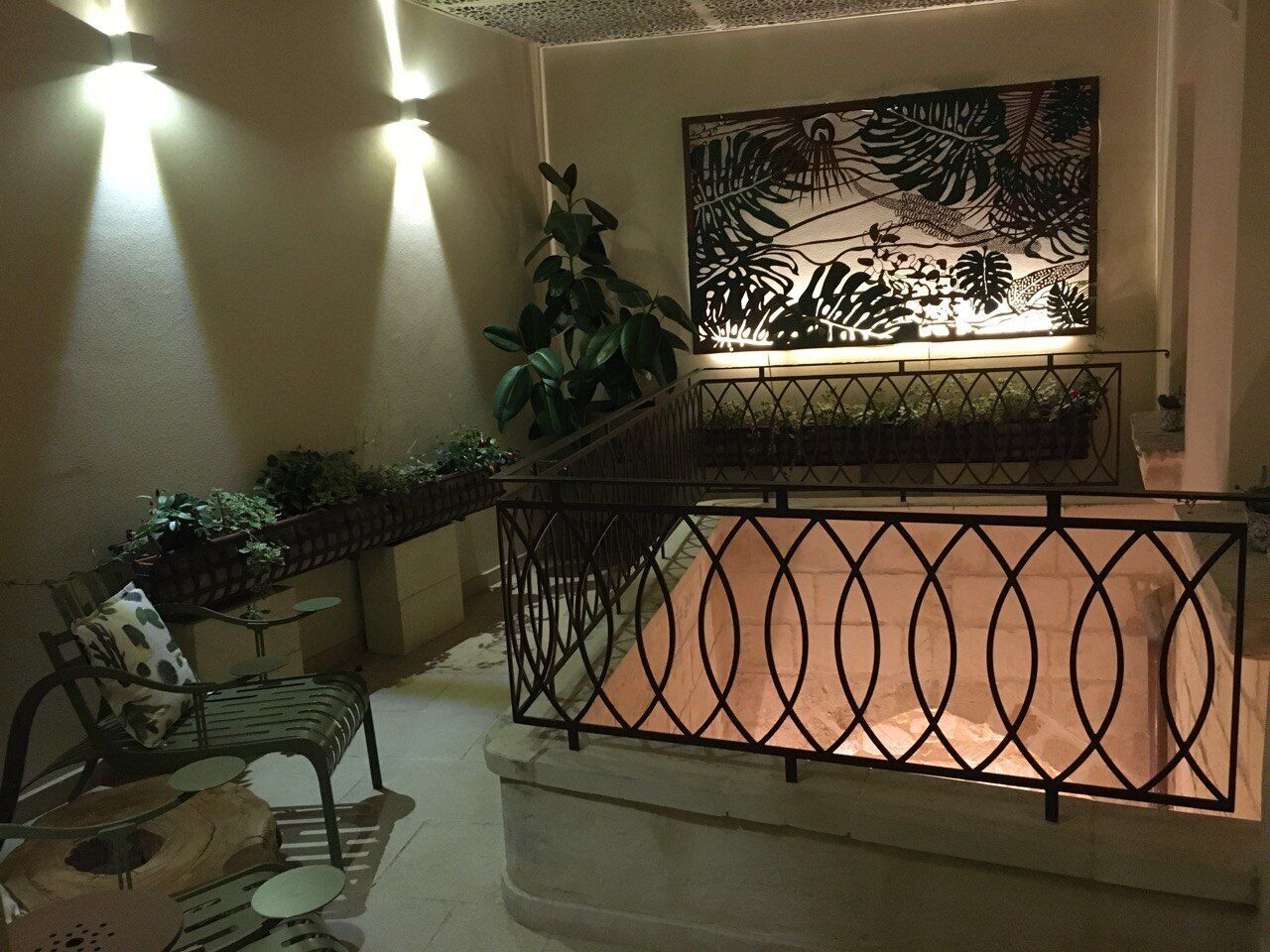 A balcony with a metal railing, a potted plant, and a wall-mounted artwork.