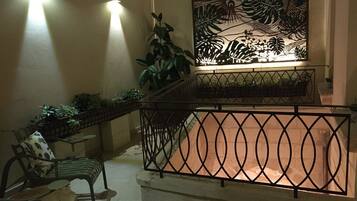 A balcony with a metal railing, a potted plant, and a wall-mounted artwork.