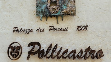 A sign for "Pollicastro Boutique Hotel" with a decorative emblem and the year "1508" above it.