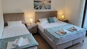 Een hotelkamer met twee bedden, een schilderij van een brug, houten vloeren en een raam met gordijnen.