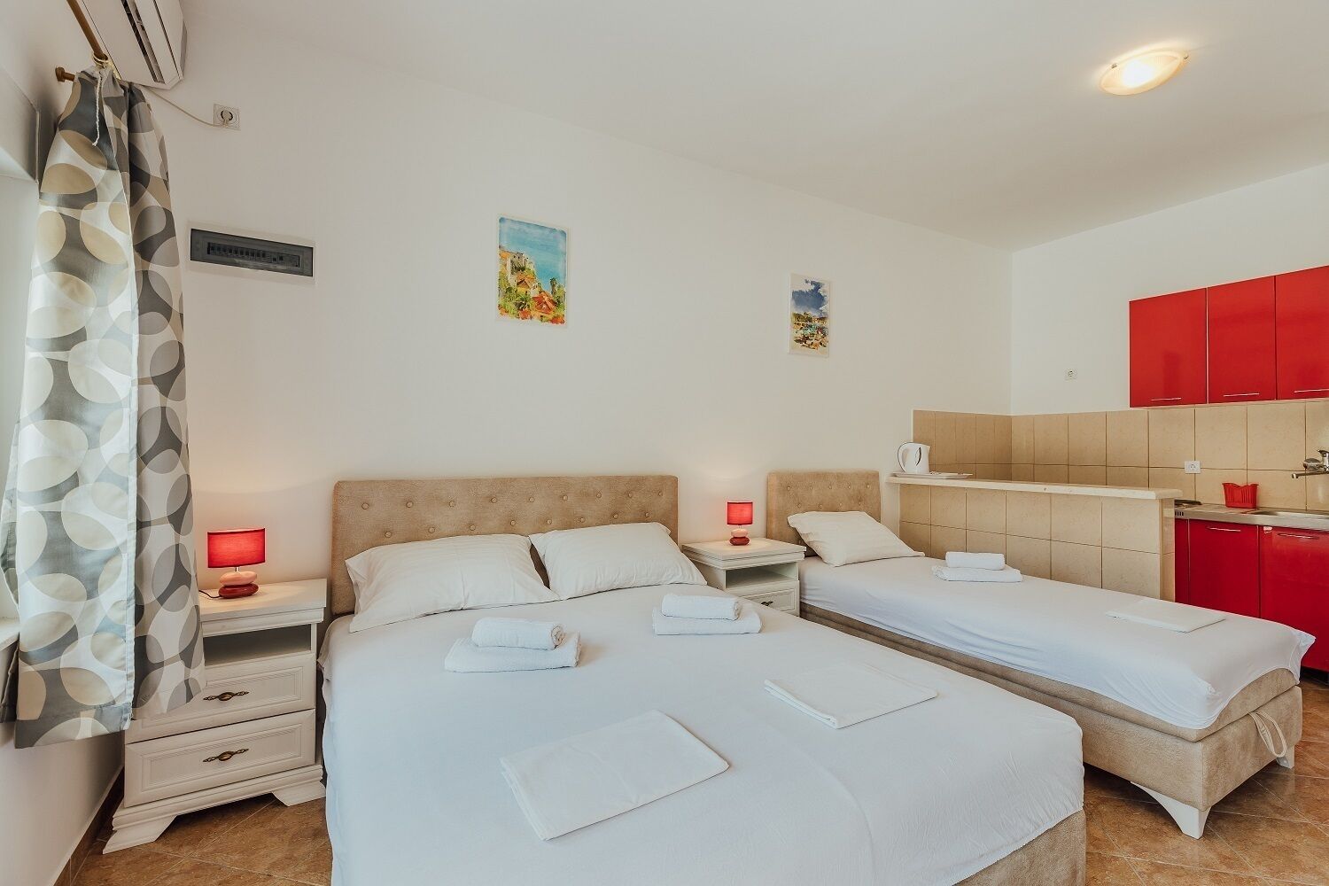 Una habitación de hotel con dos camas, una kitchenette pequeña y un baño.