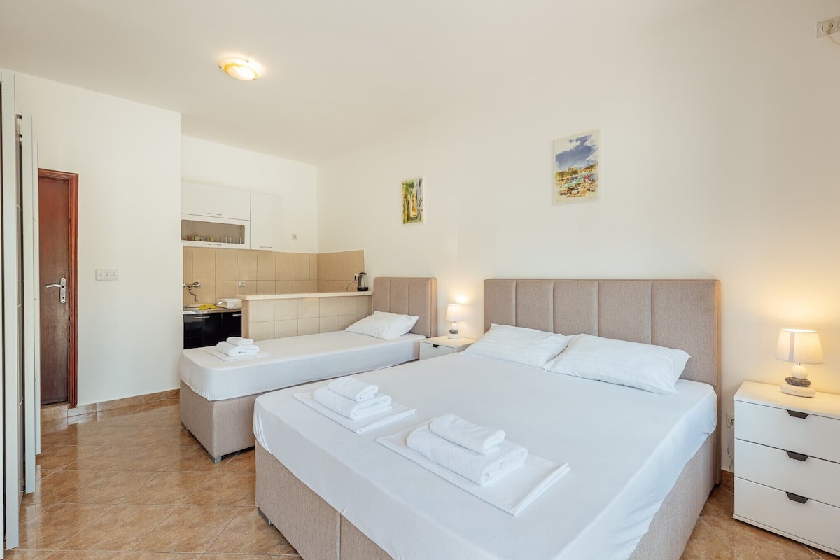 Ein Hotelzimmer mit zwei Betten, einer kleinen Küchenzeile und einem Badezimmer.