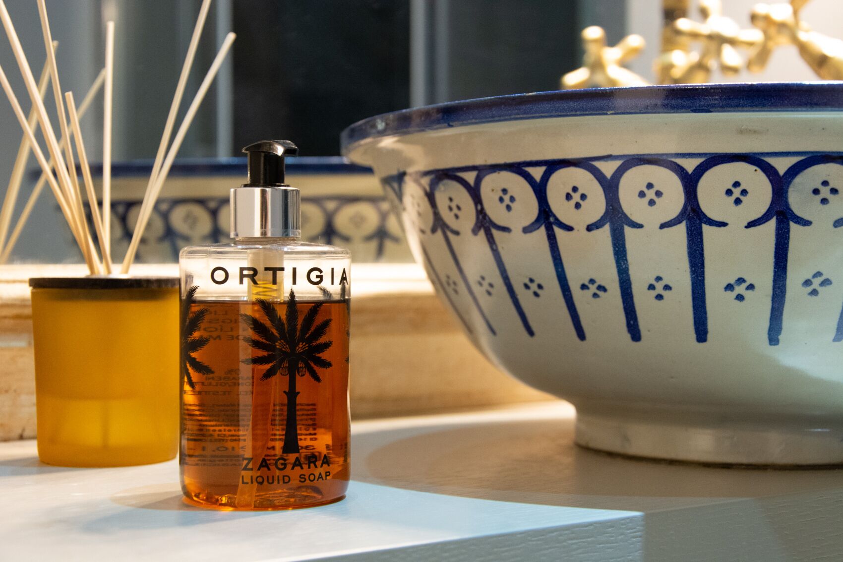 A bottle of liquid soap and a decorative bowl on a table.