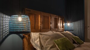 A bedroom with a wooden headboard, white bedding, and two blue patterned wall lamps. - Casa Bellezia Santa Maria - Design and history in the heart of Turin (Torino)