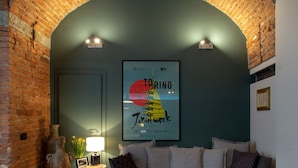 A cozy living room with a brick archway, a sofa, a lamp, and a framed poster of Tokyo. - Casa Bellezia Santa Maria - Design and history in the heart of Turin (Torino)