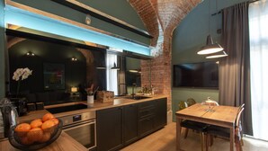 A modern kitchen with a brick wall, wooden countertops, and a dining area with a table and chairs. - Casa Bellezia Santa Maria - Design and history in the heart of Turin (Torino)