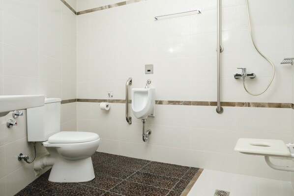 A modern bathroom with a toilet, urinal, and shower.