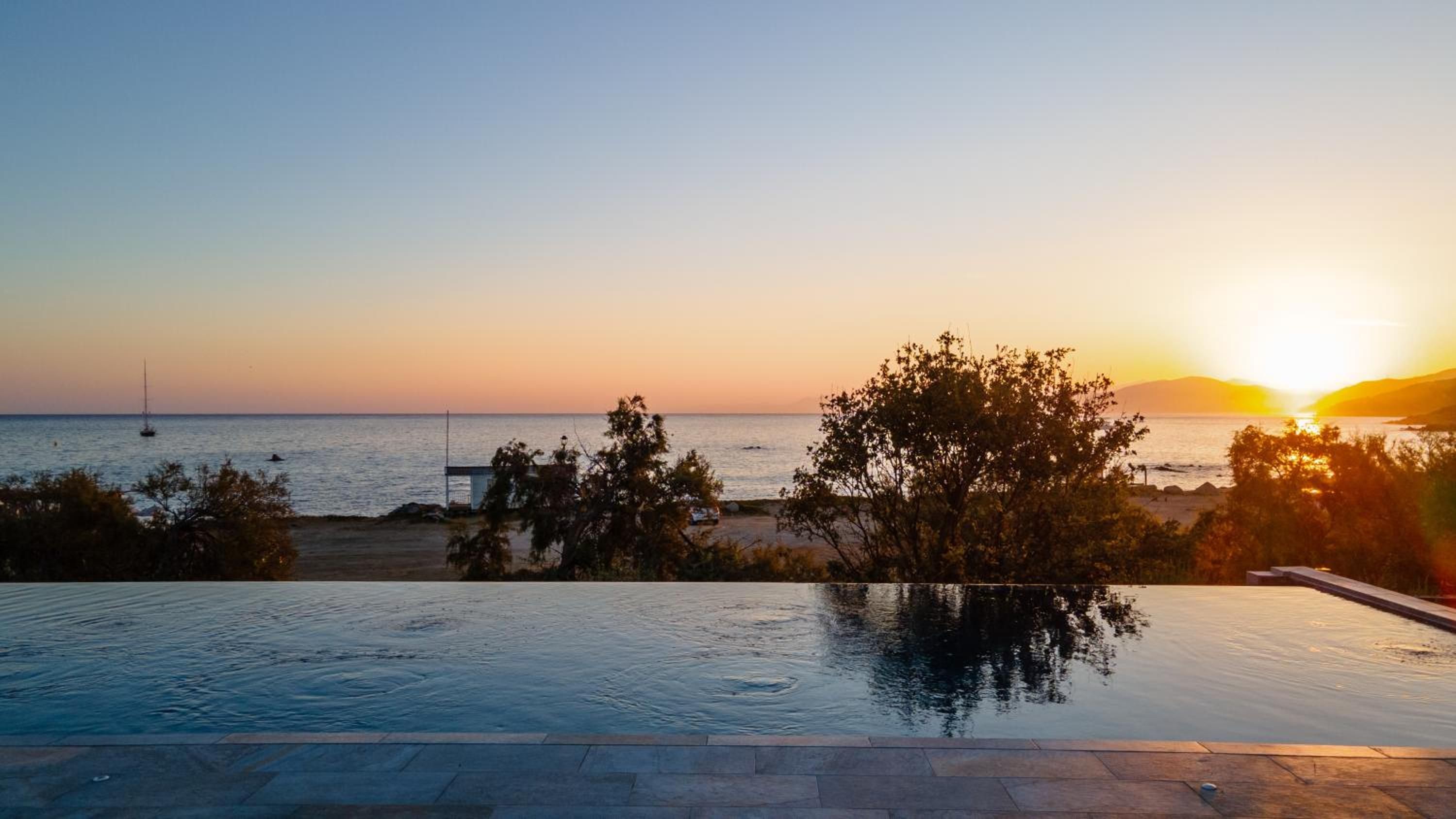 Una piscina con vista al mar y al atardecer.