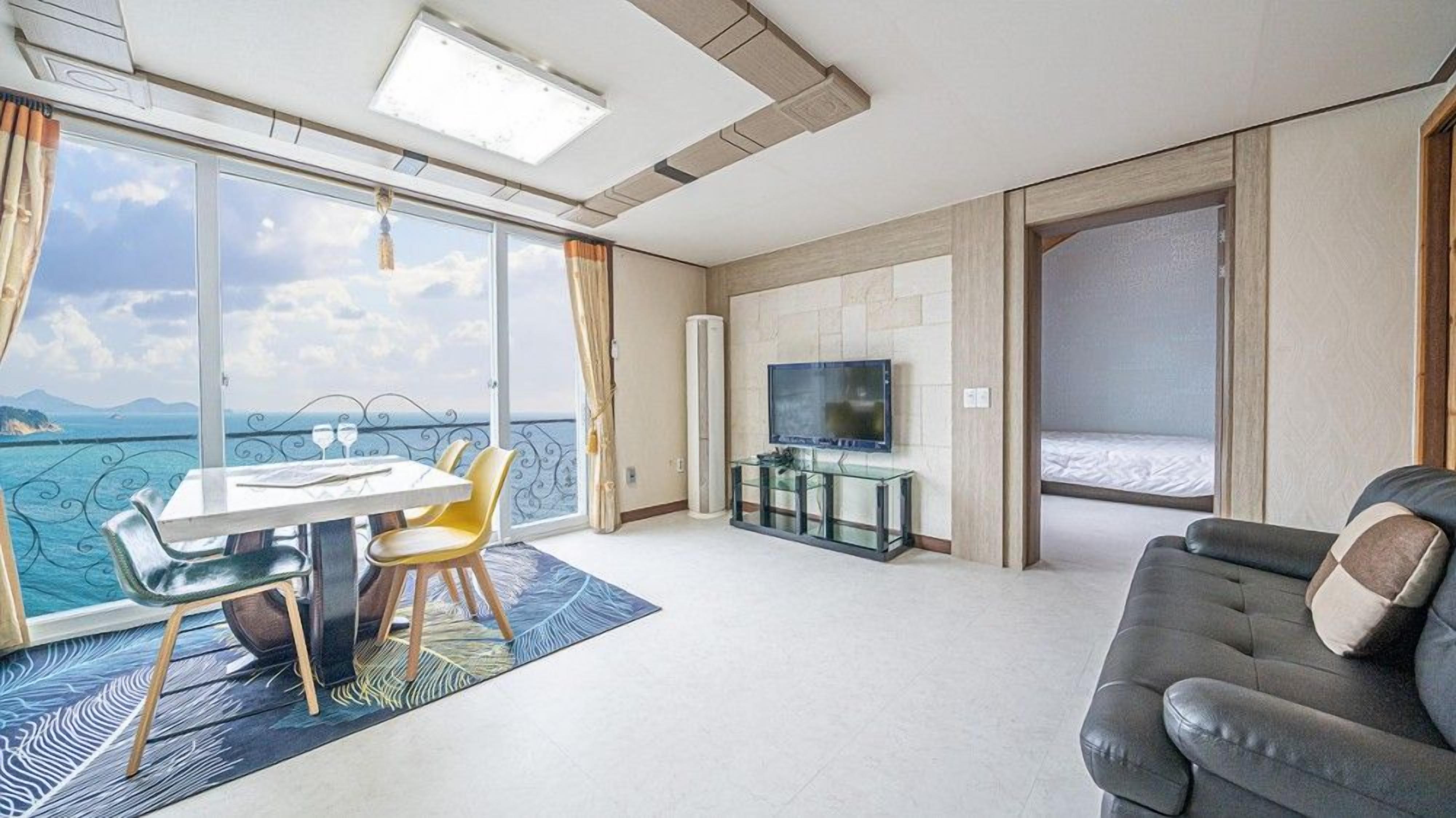 Ett modernt hotellrum med en stor balkong, en matplats, en TV och en soffa.