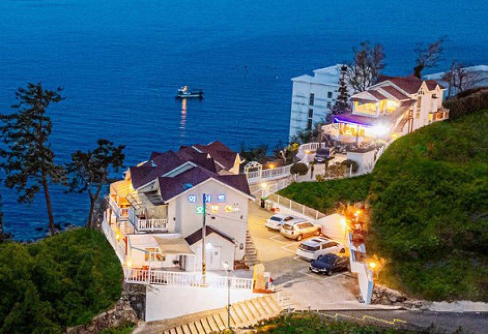 Un hotel costero con varias edificaciones, un estacionamiento y vistas al mar.