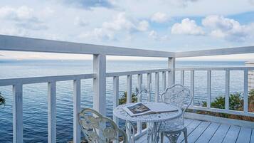 En hvid udendørs terrasse med et bord og stole med udsigt over havet.