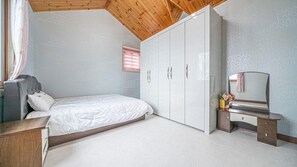 Un dormitorio con cama, armario, escritorio y espejo.