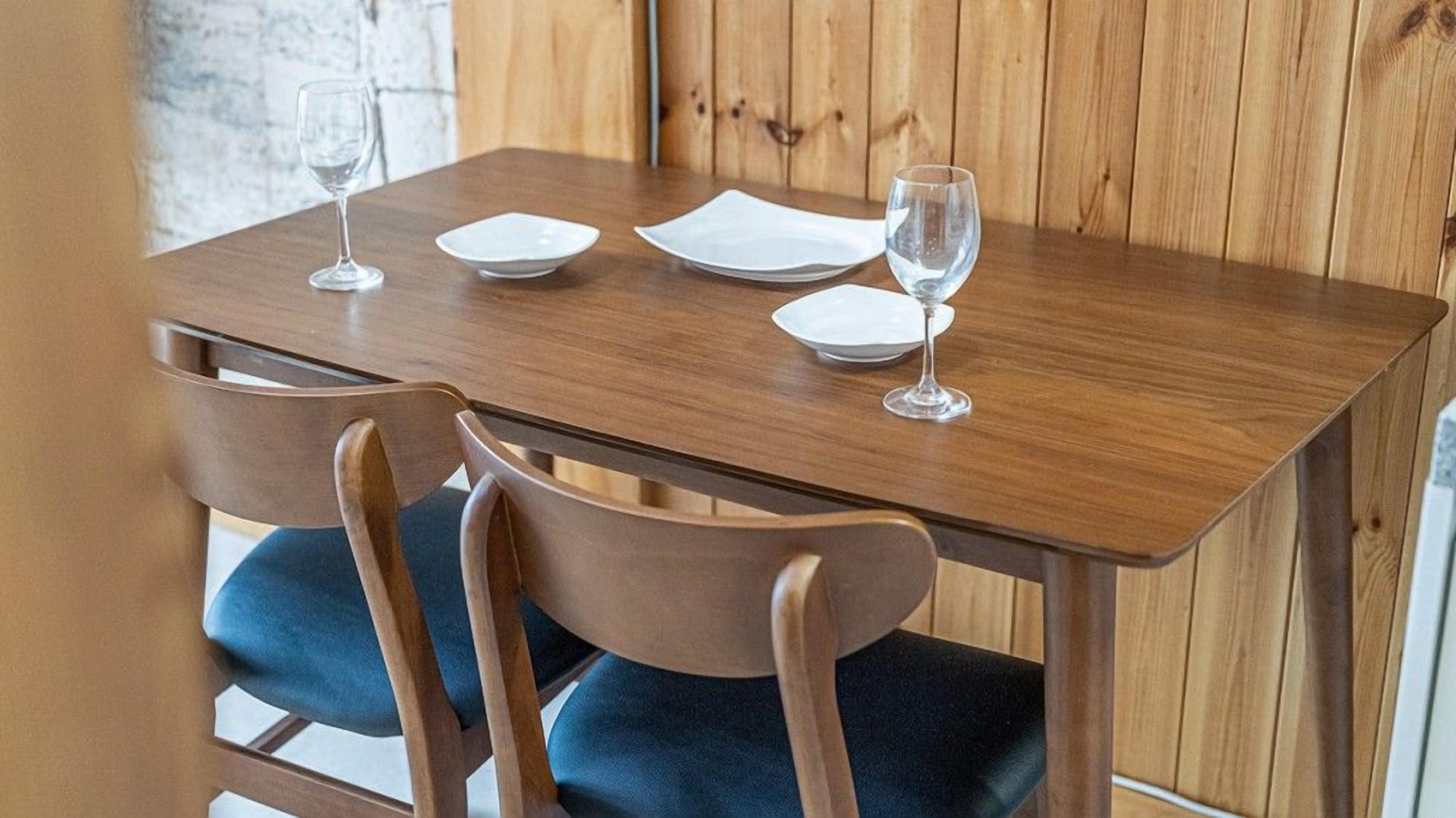 Une table en bois avec quatre assiettes blanches et deux verres à vin.