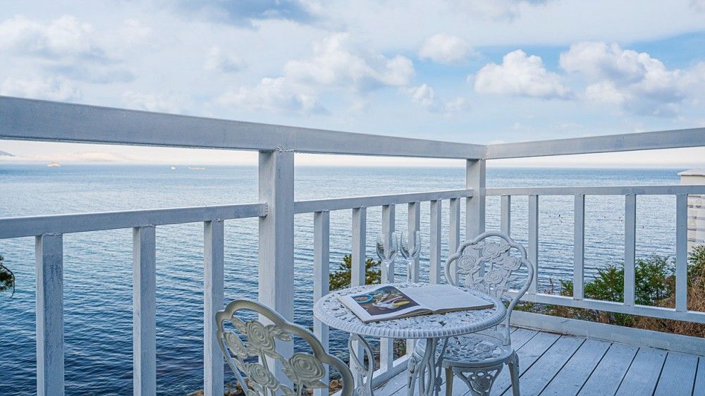 Una terraza exterior blanca con mesa y sillas con vistas al mar.