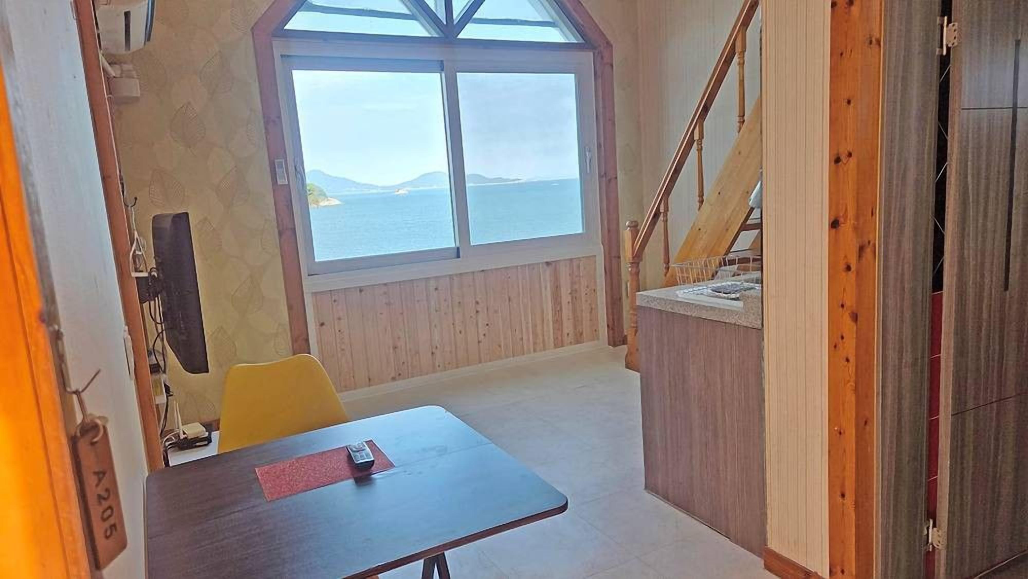 Une pièce dotée d’une grande fenêtre, d’un escalier en bois et d’une table avec une télécommande.