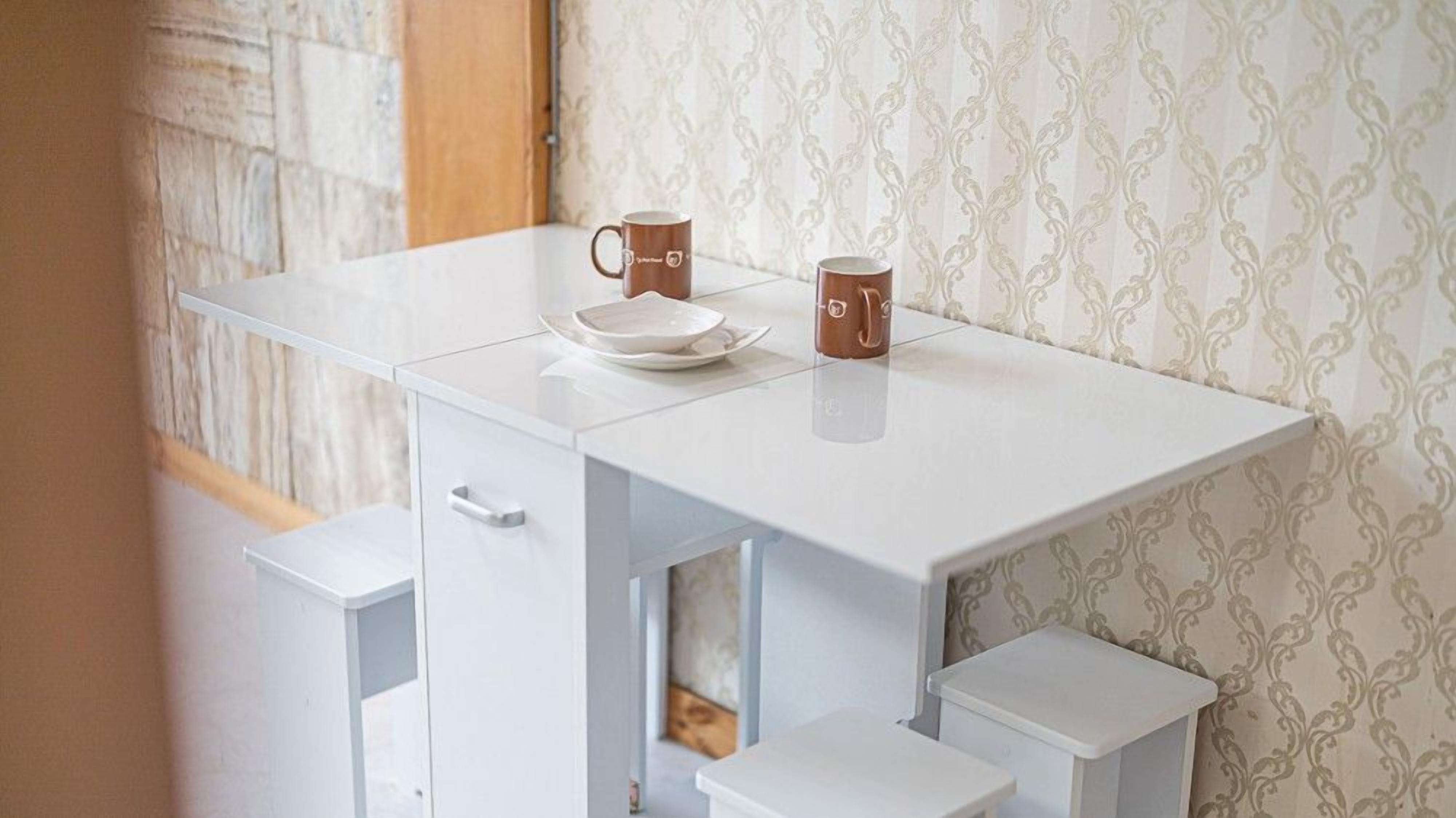 A white table with two brown mugs and a white plate.