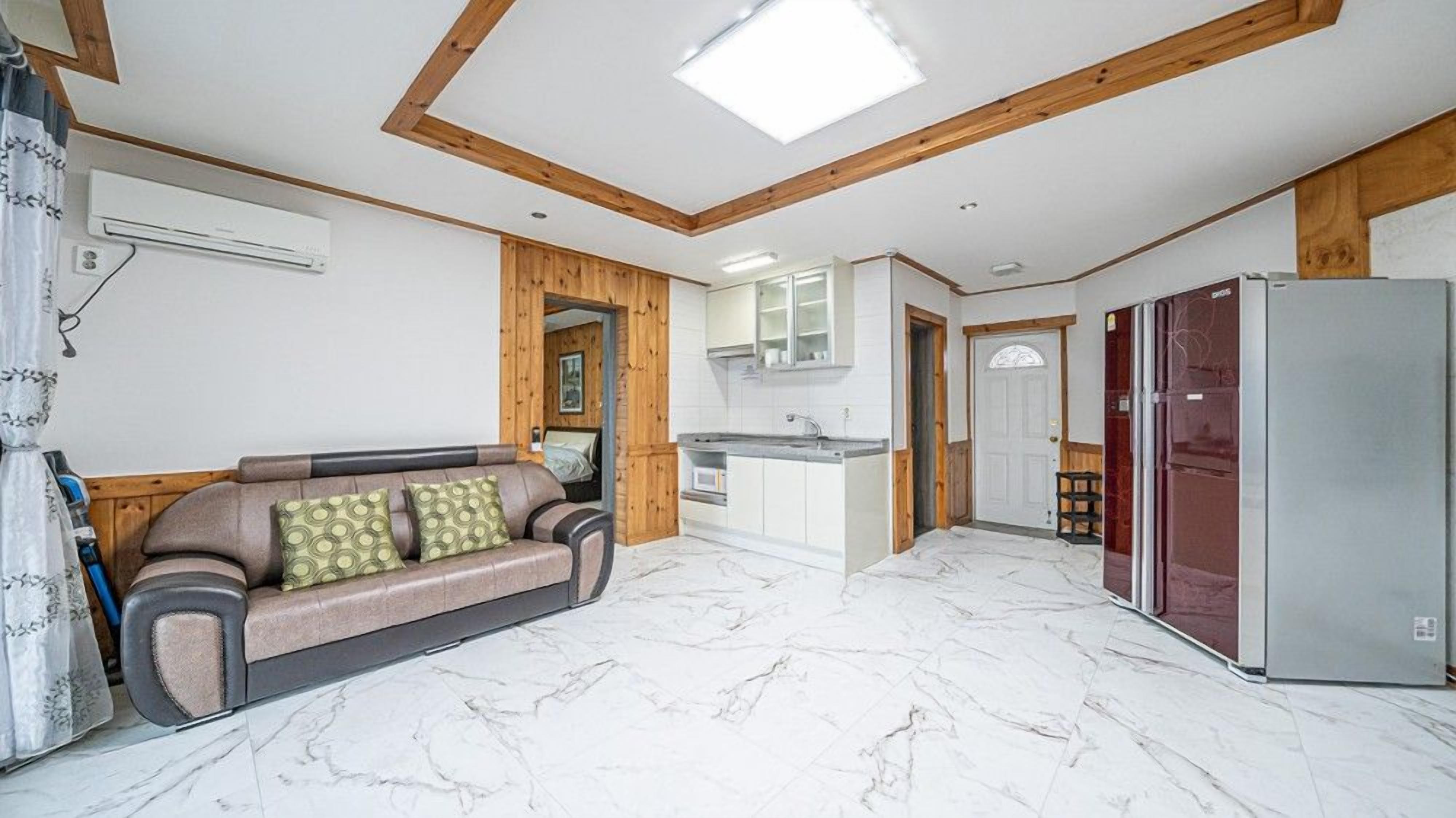 A modern kitchen with a marble floor, wooden accents, and a built-in refrigerator.