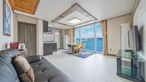Una sala de estar moderna con un sofá, un comedor con sillas, una cocina y un balcón con vistas.