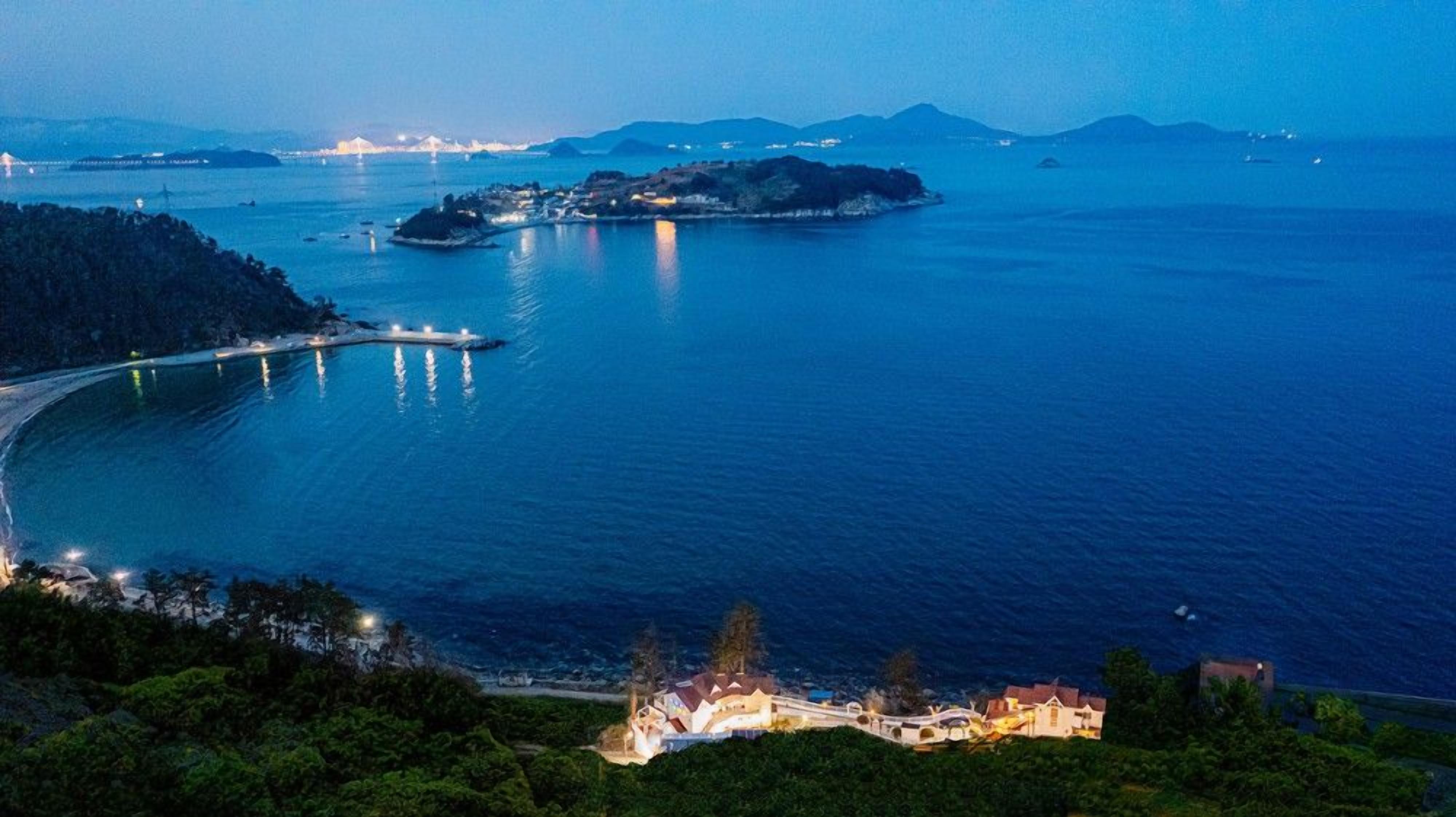 Una zona costera con un puente, una pequeña isla y un poblado con edificios.