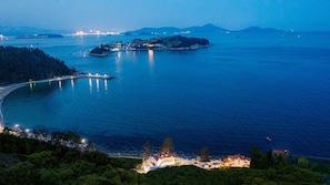 A coastal area with a bridge, a small island, and a settlement with buildings. - White O Pension (Geoje)