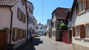 Eine enge Kopfsteinpflasterstraße, gesäumt von traditionellen Gebäuden im europäischen Stil, darunter Fachwerkhäuser und Satteldächer.